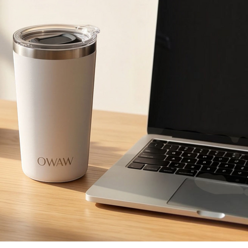 OWAW Pause stainless steel travel mug in White on a desk beside a laptop
